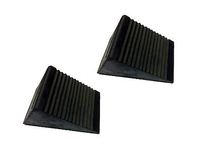 A pair of black rubber wheel chocks with a ribbed design.